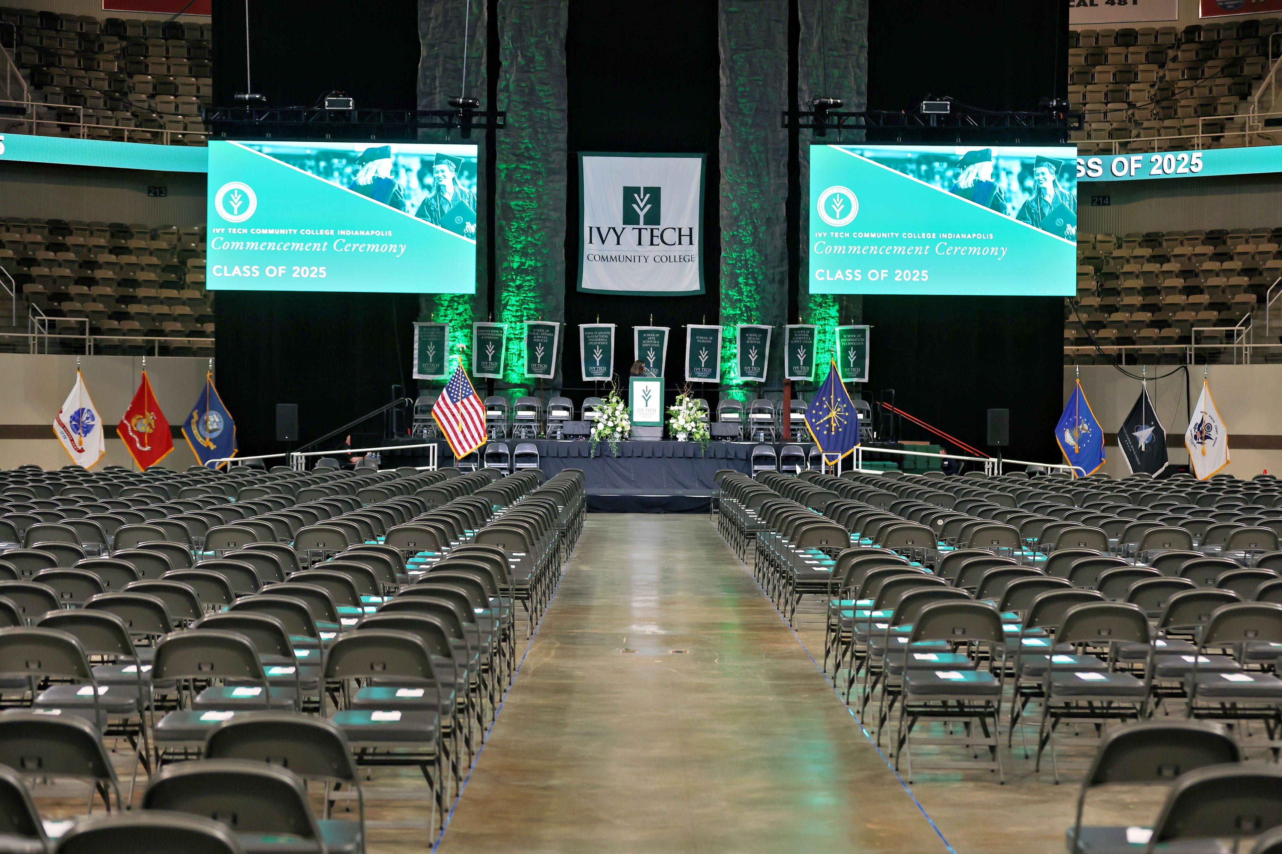 A graduation ceremony held in an indoor gymnasium with graduates and an audience.