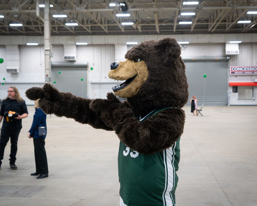 Side view of a young graduate in cap and gown in a school hallway.