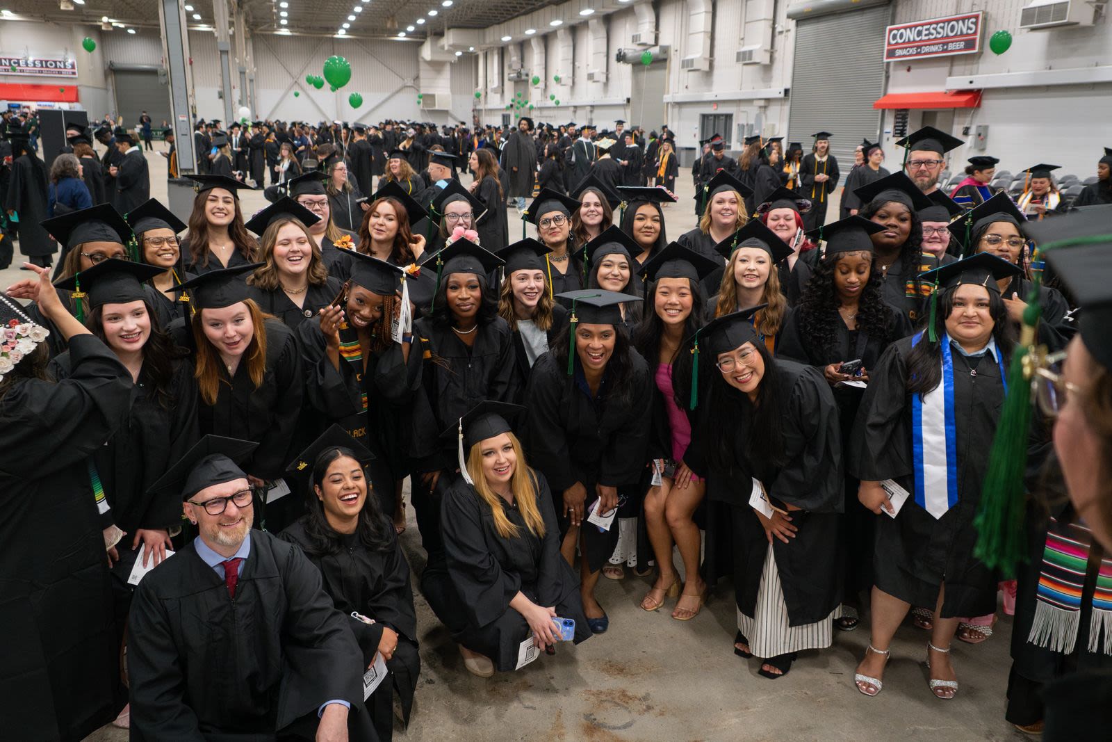Two graduates in caps and gowns celebrating their achievement on stage.
