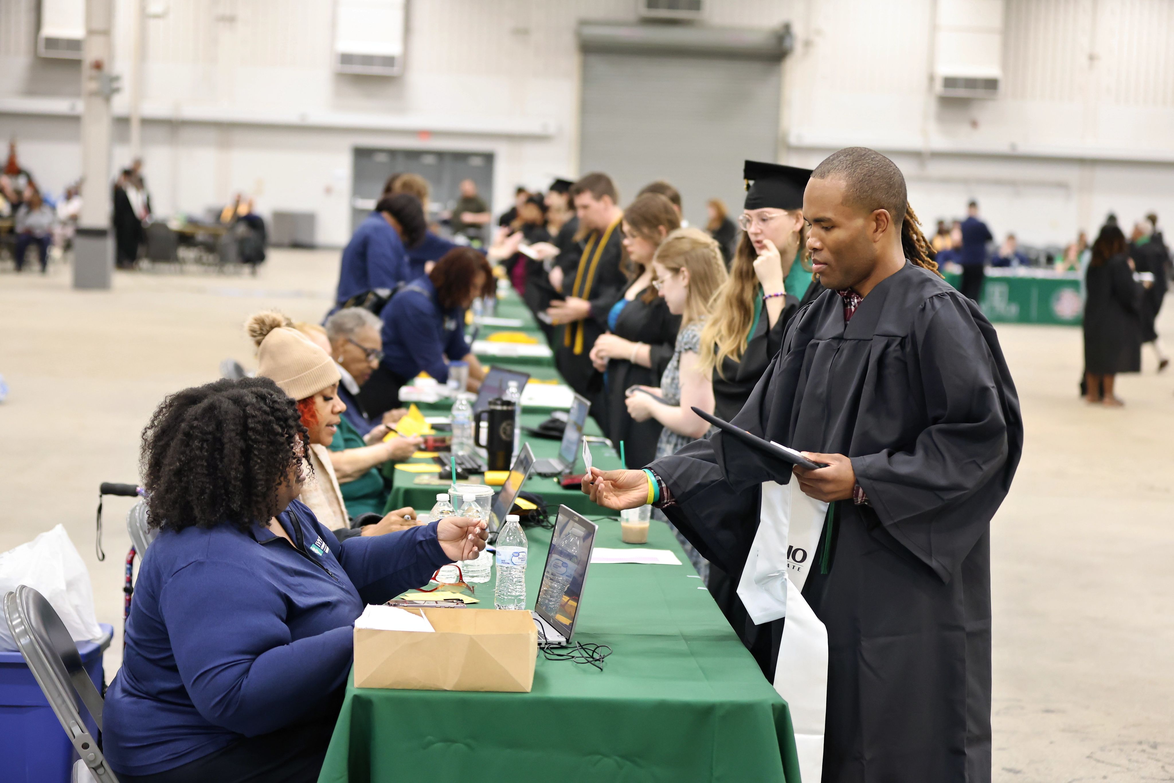 Graduates in caps and gowns toss hats in the air.