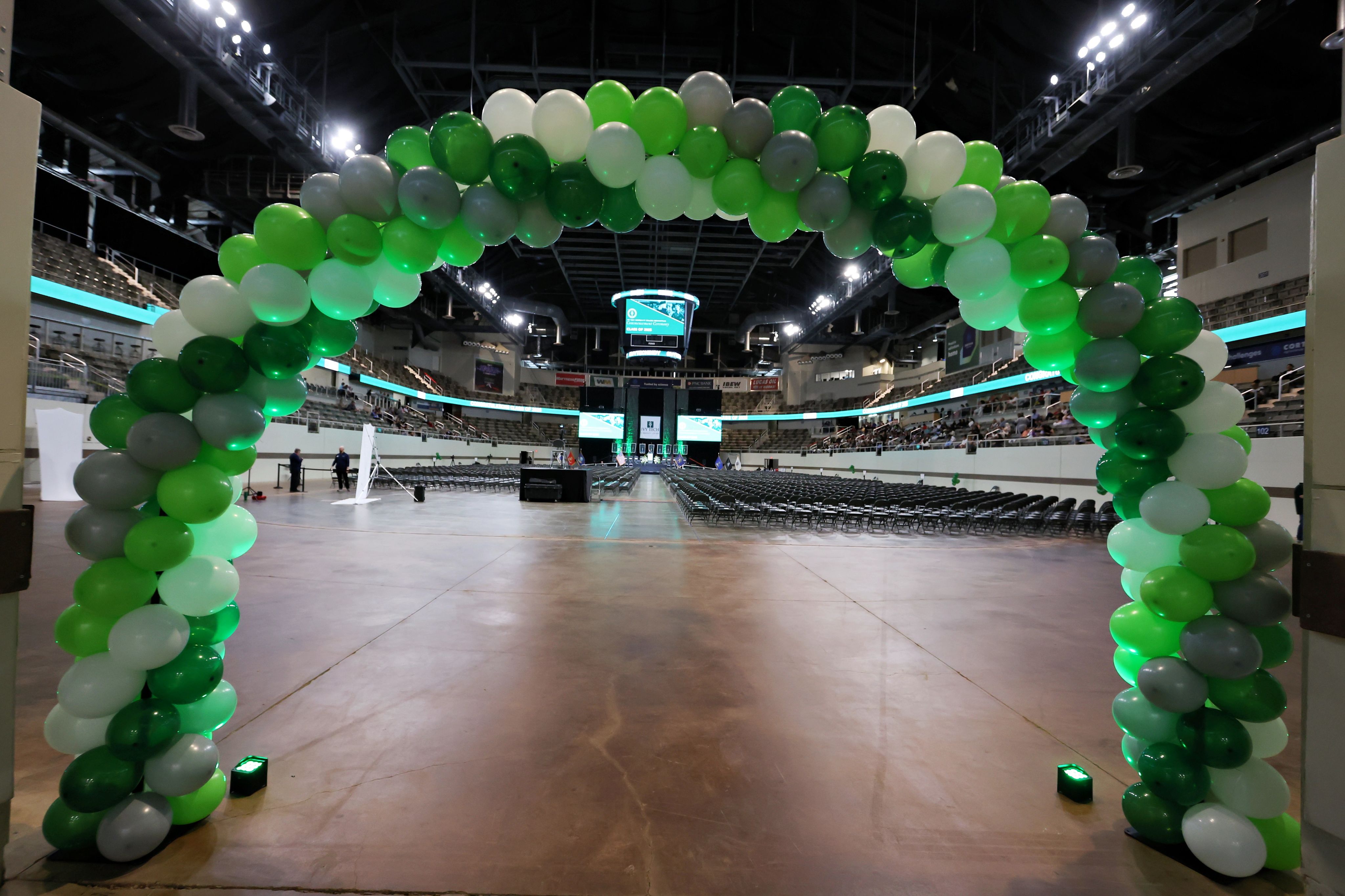 Two graduates in caps and gowns celebrating their achievement on stage.